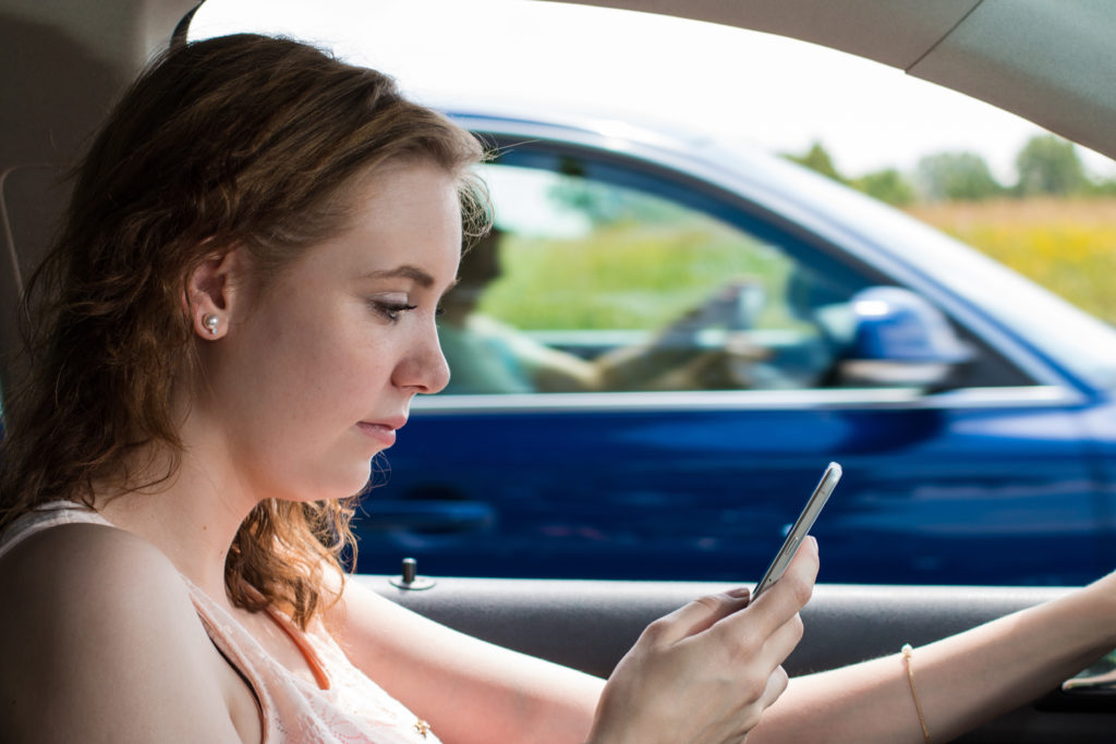 Florida woman demonstrating distracted driving by staring at her phone.